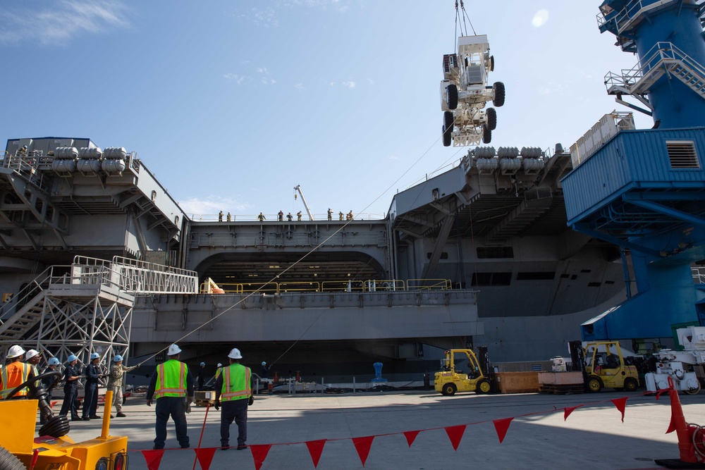 Sailors onload the aircraft crash and salvage crane onto the flight deck of Abraham Lincoln.