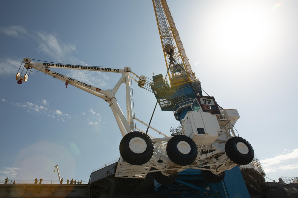 Sailors onload the aircraft crash and salvage crane onto the flight deck of Abraham Lincoln.