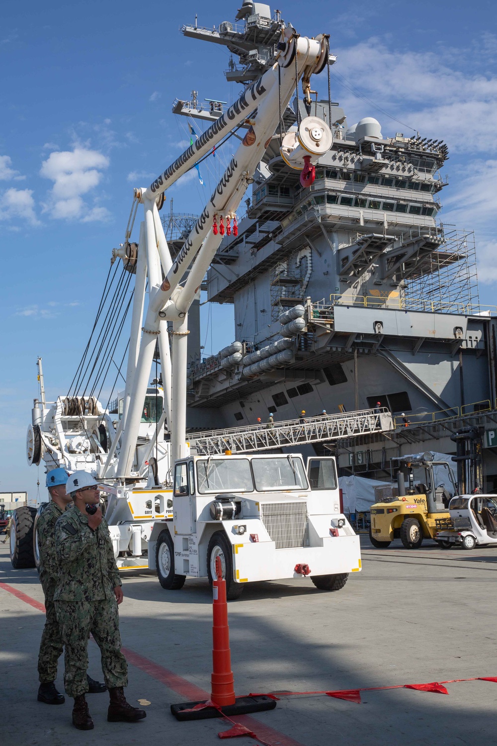 Sailors onload the aircraft crash and salvage crane onto the flight deck of Abraham Lincoln.