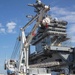 Sailors onload the aircraft crash and salvage crane onto the flight deck of Abraham Lincoln.