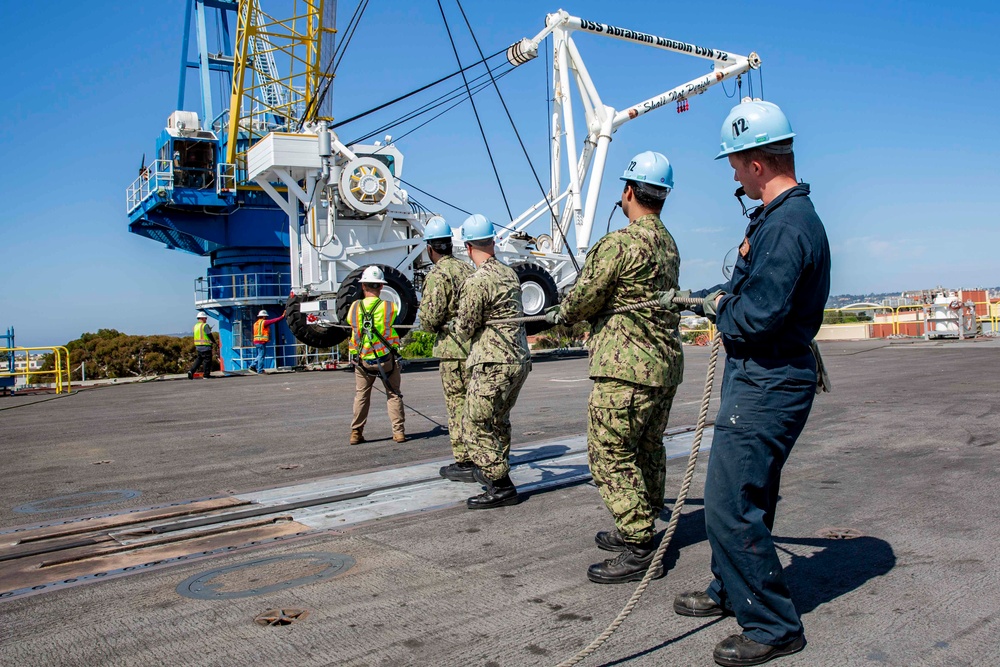 Sailors onload the aircraft crash and salvage crane onto the flight deck of Abraham Lincoln