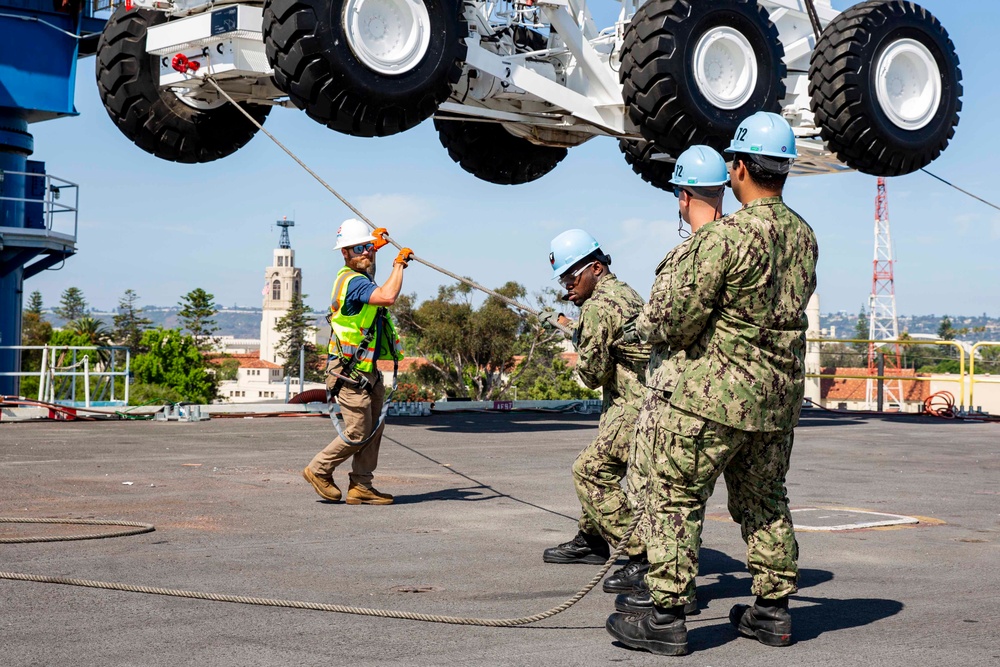 Sailors onload the aircraft crash and salvage crane onto the flight deck of Abraham Lincoln