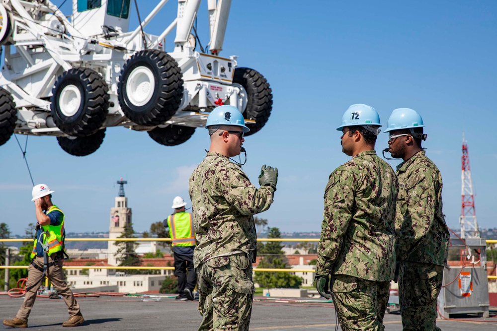 Sailors onload the aircraft crash and salvage crane onto the flight deck of Abraham Lincoln