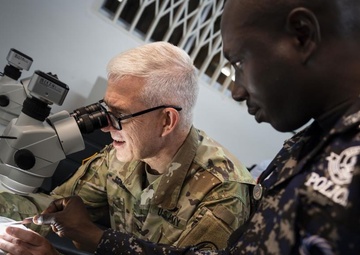 U.S. Army Col. Tom Eccles, United States Africa Command surgeon, identifies different mosquito species through a microscope with Deputy Superintendent of Police Emmanuel Baba Asabila, Ghana Police.