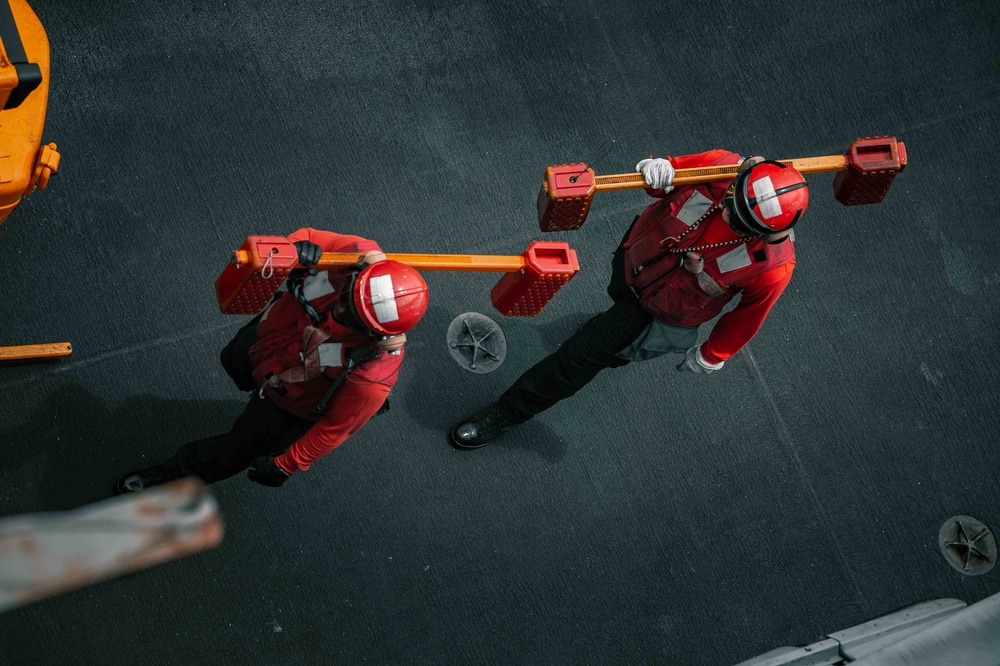 Sailors carry equipment on the flight deck of USS Carl Vinson (CVN 70)