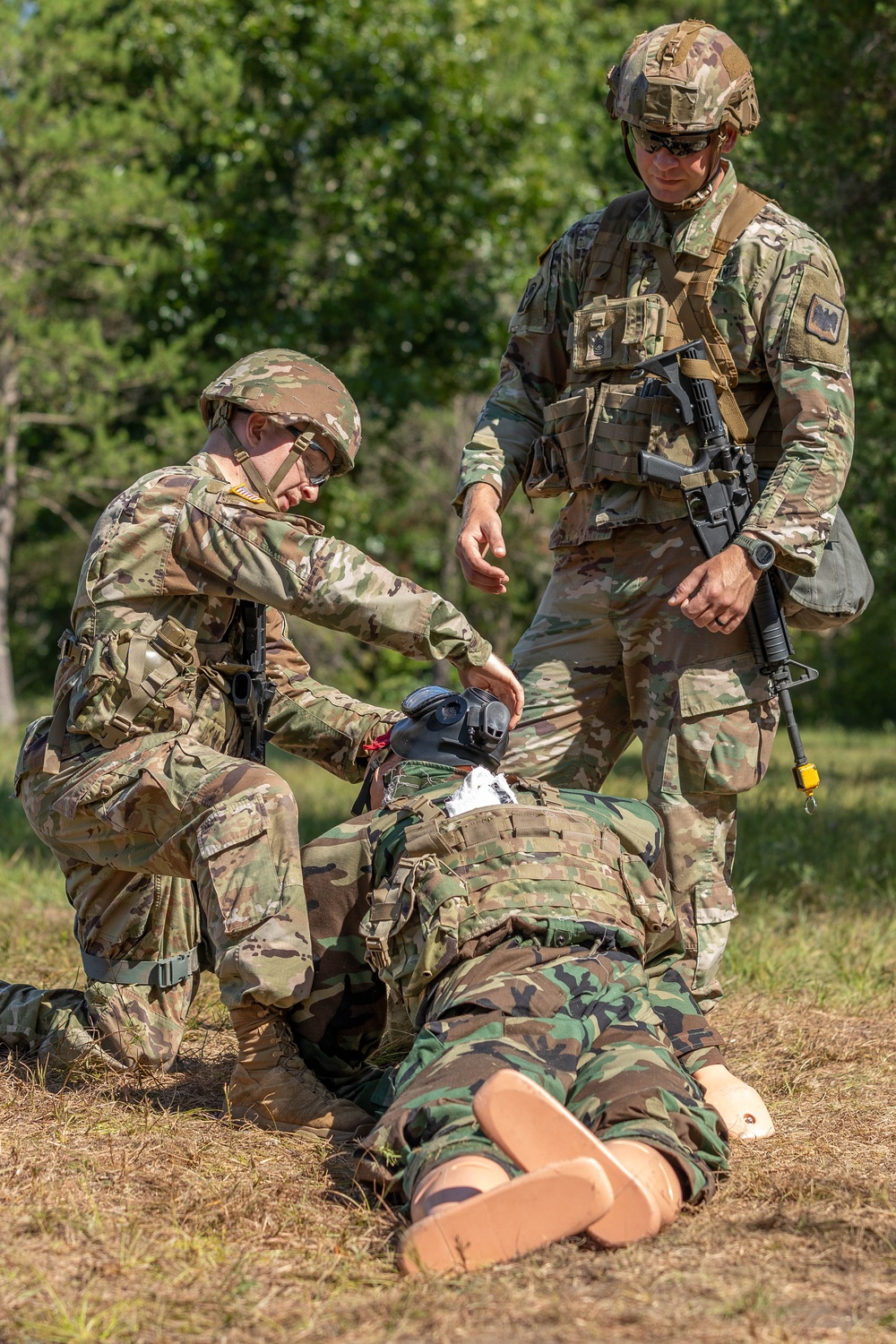 Private 1st Class Tyson Clark assesses a head injury as Master Sgt. Steven Kiser looks on