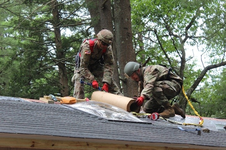 990th Engineer Vertical Construction Company Soldiers install shingles on the roof of the Devens Reserve Forces Training Facility range gas chamber in Devens, Mass., August 4, 2023.