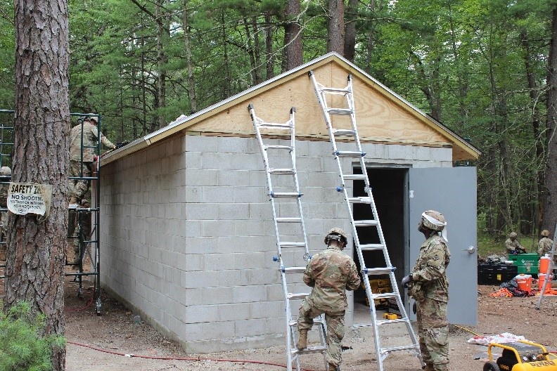 990th Engineer Vertical Construction Company Soldiers begin installing shingles onto the roof of the new concrete gas chamber on Devens Reserve Forces Training Facility range gas chamber in Devens, Mass., August 4, 2023.