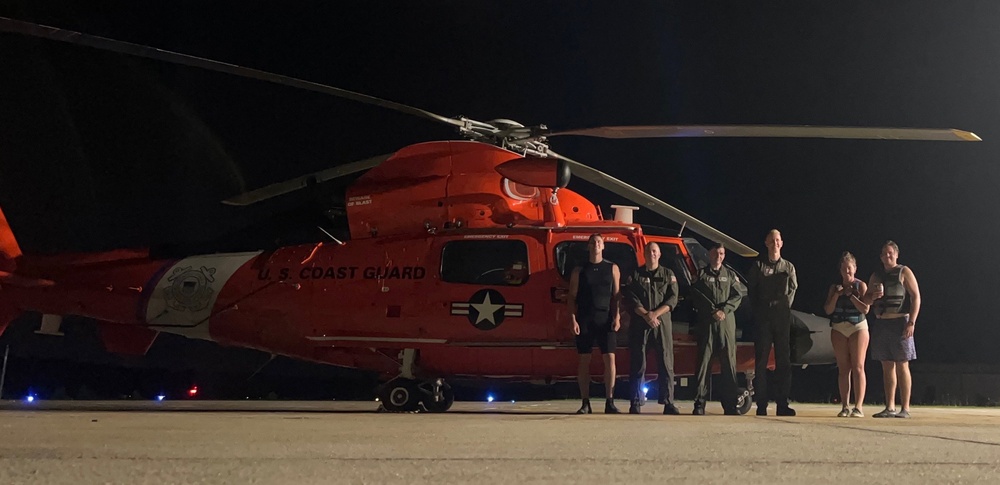 A Coast Guard Air Station Savannah helicopter crew poses for picture with two rescued jet skiers at Charleston Executive Airport in Johns Island, South Carolina, Aug. 22, 2023. The jet skiers were hoisted after they became stranded on Morris Island near Charleston, South Carolina. U.S. Coast Guard photo, courtesy Air Station Savannah)