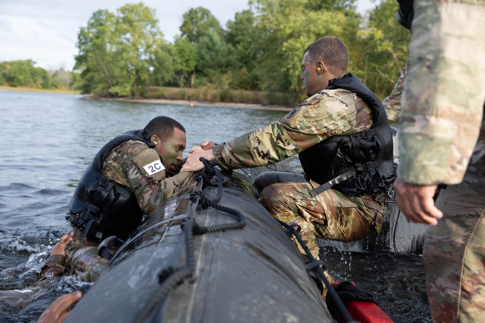 Spc. Nathaniel Wells helps teammate Spc. Maynard Delphin into a zodiac boat