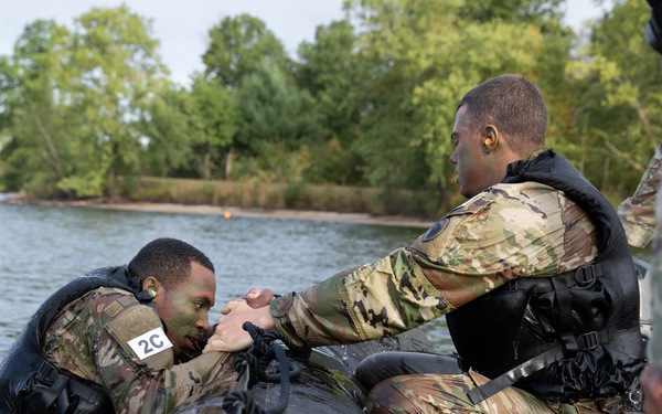 Spc. Nathaniel Wells helps teammate Spc. Maynard Delphin into a zodiac boat