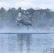 U.S. Army Reserve Best Squad competitors float in the water as their teammate jumps out of a CH-47 Chinook