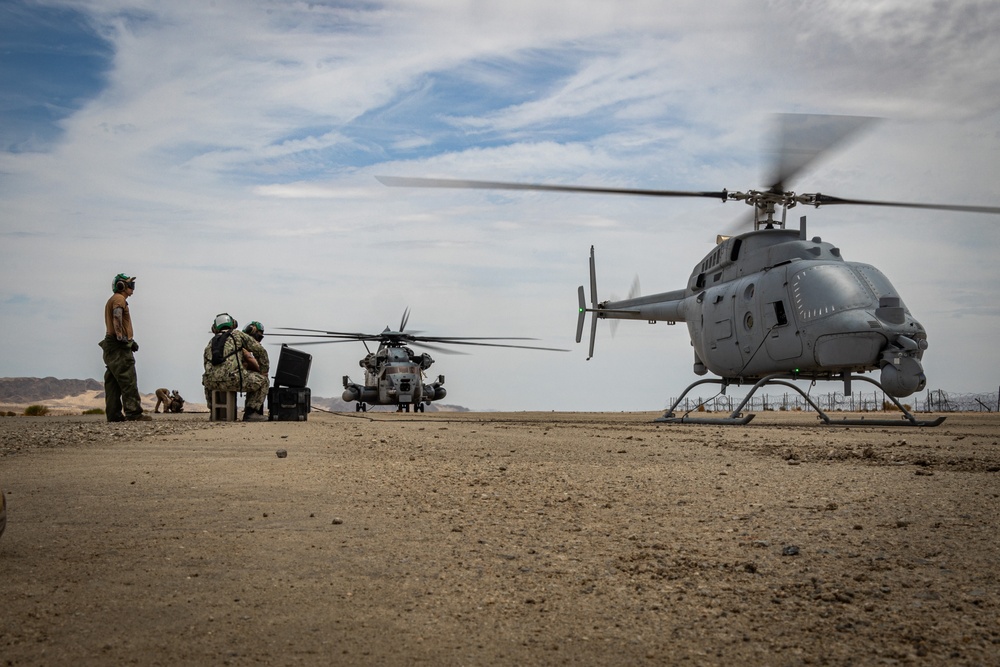 A CH-53E Super Stallion first time ground refueling a U.S. Navy MQ-8C Fire Scout unmanned helicopter