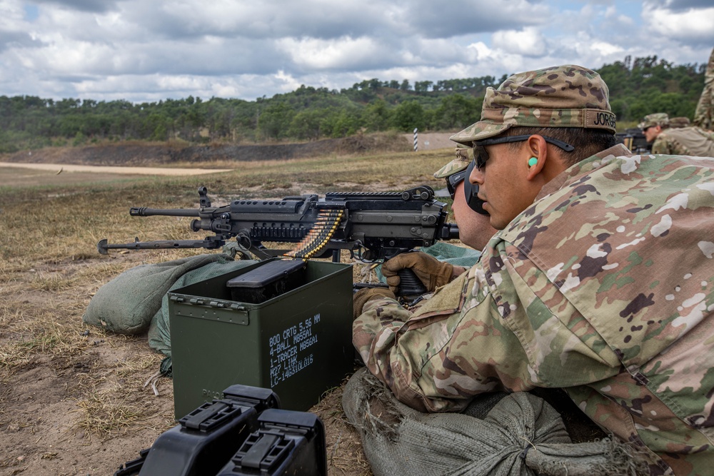 Spc. Hayse Jorgensen spots targets down range as Sgt. Connor Housman fires an M249 machine gun