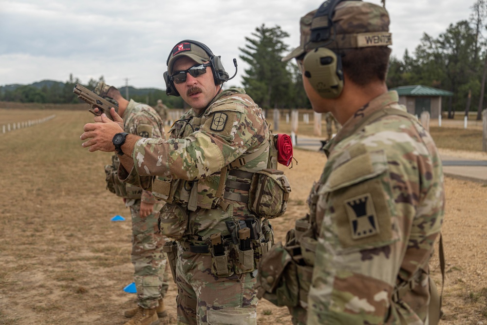 Staff Sgt. Daniel Kelley instructs Pfc. Vincent Wentorf on M17 pistol marksmanship