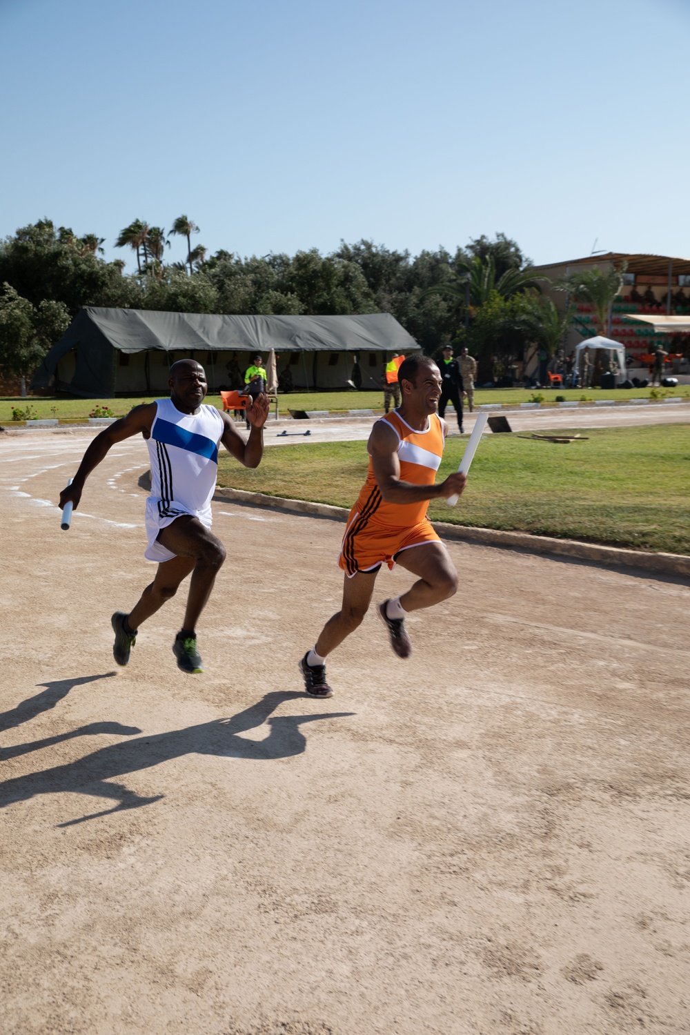 Military personnel from multiple countries run in an organized track meet