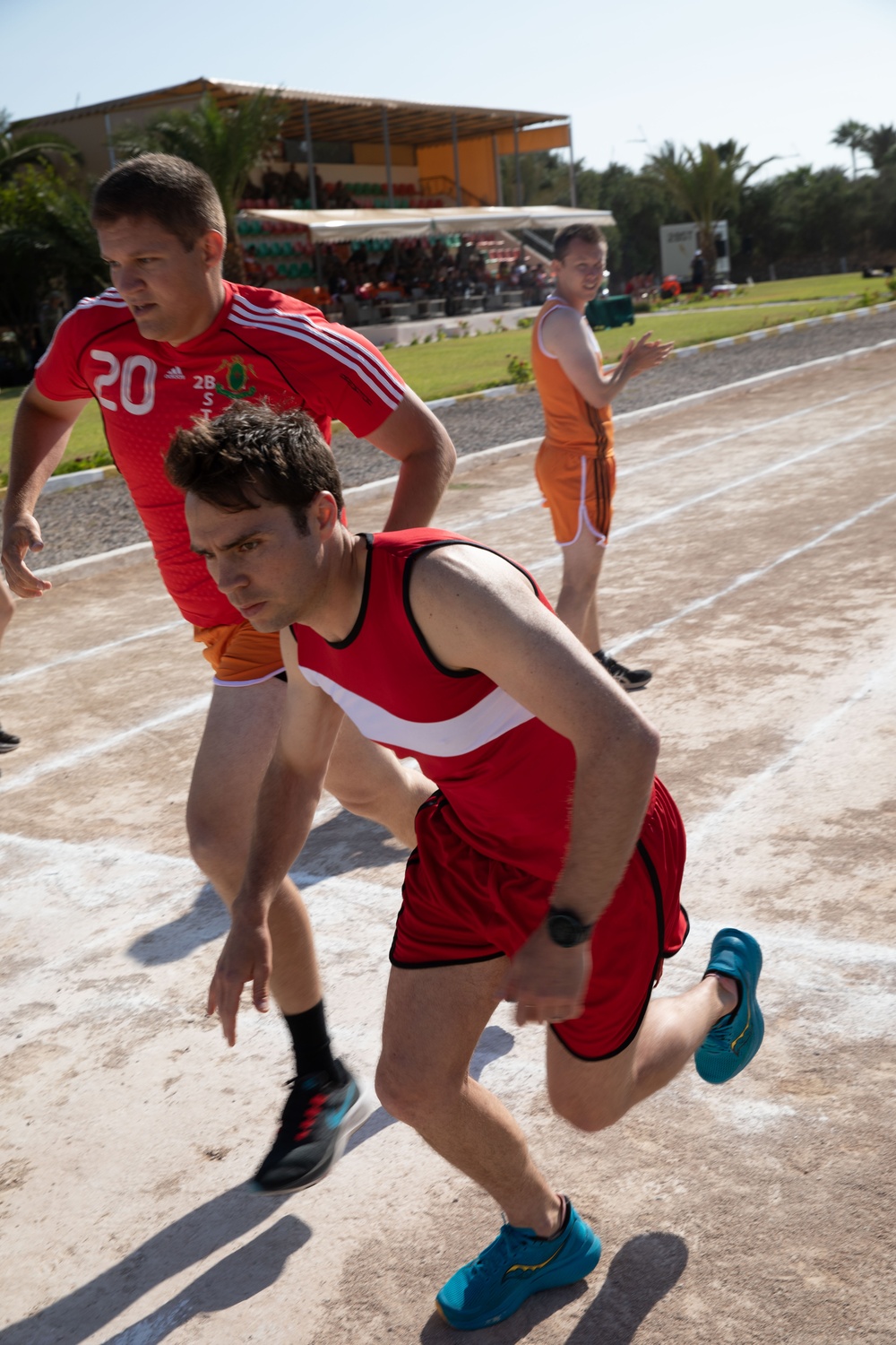 Military personnel from multiple countries run in an organized track meet