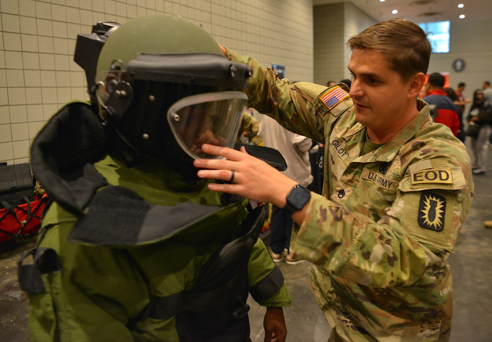 Soldier assisting man to demonstrate EOD equipment