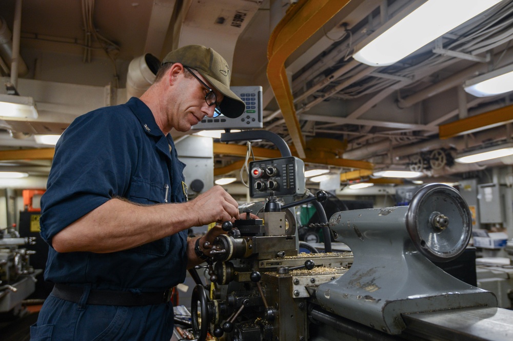 U.S. Navy Sailor Makes Adjustments To A Lathe