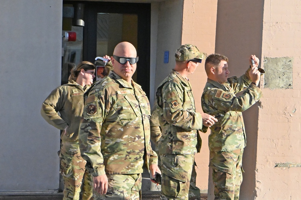 A group of 173rd Fighter Wing Airmen look toward the sun during the solar eclipse using special glasses.