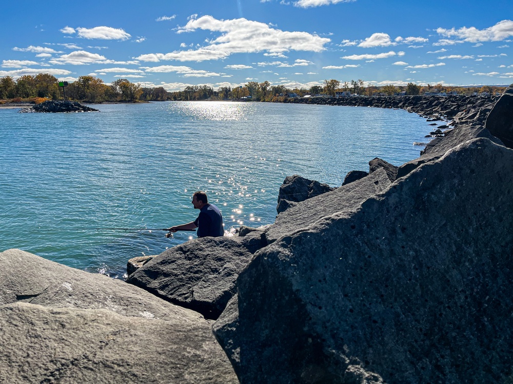 Fisherman casts line from harbor breakwall