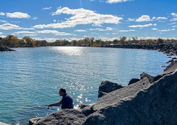 Fisherman casts line from harbor breakwall