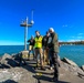 USACE engineers and local officials stand at end of harbor breakwall