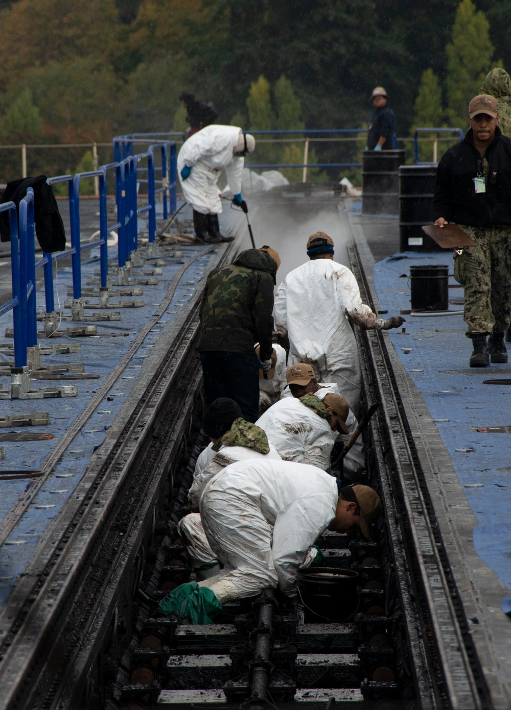 U.S. Navy Sailors Scrape Grease From Catapult Trough