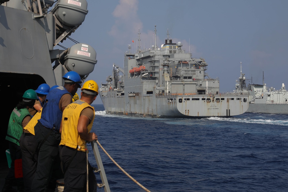 Sailors aboard the USS Rafael Peralta (DDG 115) conduct a replenishment-at-sea with the Lewis and Clark-class dry cargo USNS Wally Schirra (T-AKE-8) in the South China Sea