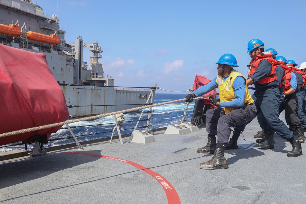 Sailors aboard the USS Rafael Peralta (DDG 115) conduct a replenishment-at-sea with the Lewis and Clark-class dry cargo USNS Wally Schirra (T-AKE-8) in the South China Sea