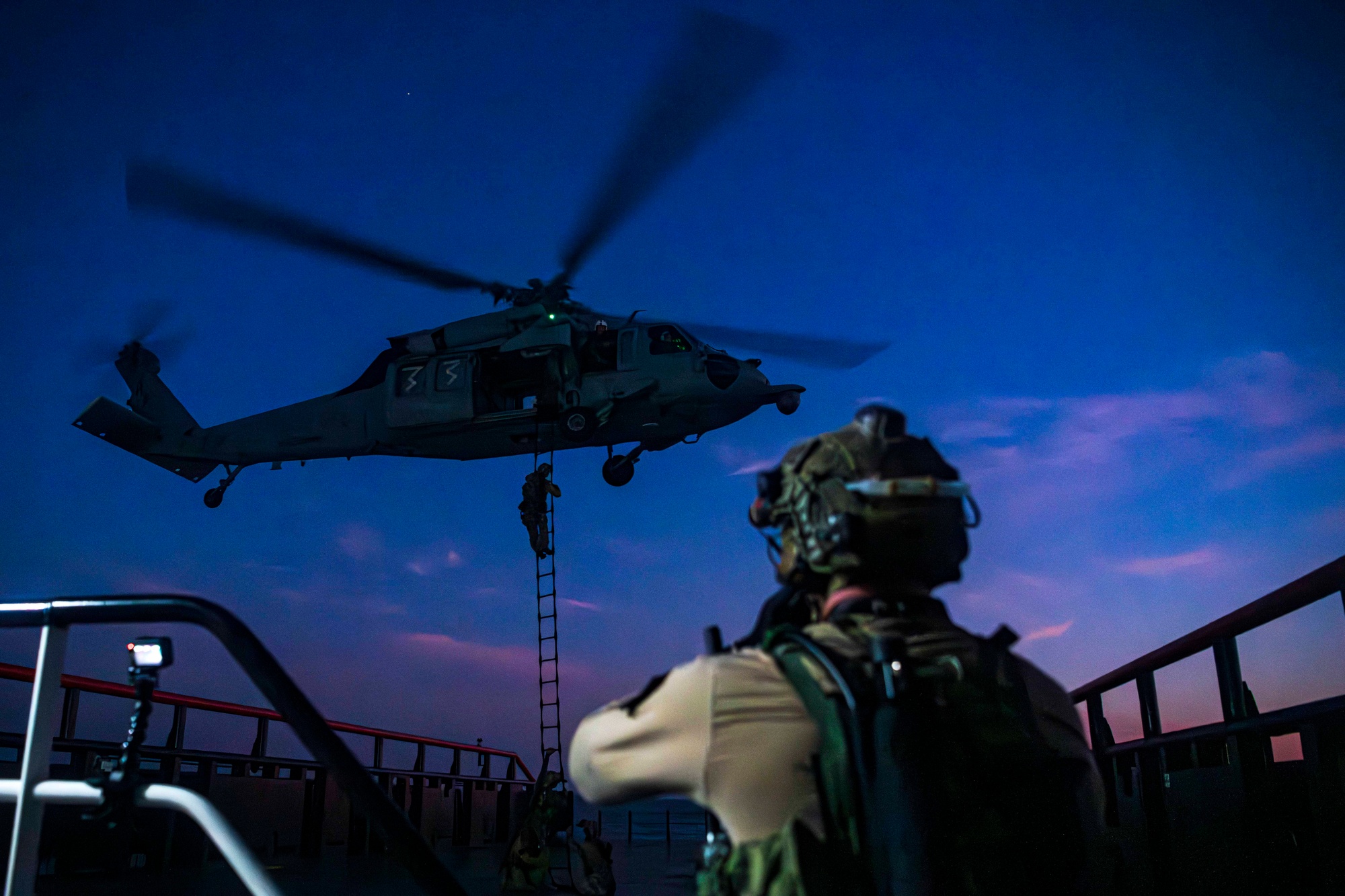 Navy SEALs from Naval Special Warfare climb a ladder into an MH-60S Seahawk helicopter during a maritime interdiction training exercise