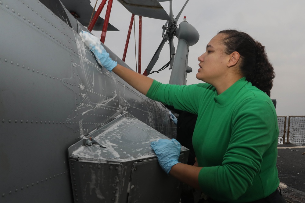 Sailors aboard the USS Rafael Peralta (DDG 115) clean a Seahawk helicopter (MH-60R) in the Sea of Japan