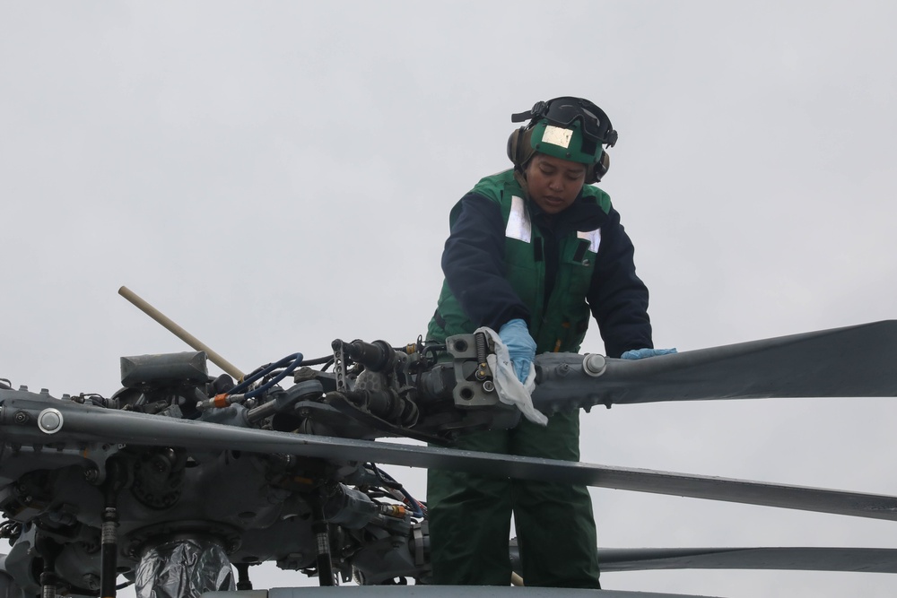 Sailors aboard the USS Rafael Peralta (DDG 115) clean a Seahawk helicopter (MH-60R) in the Sea of Japan