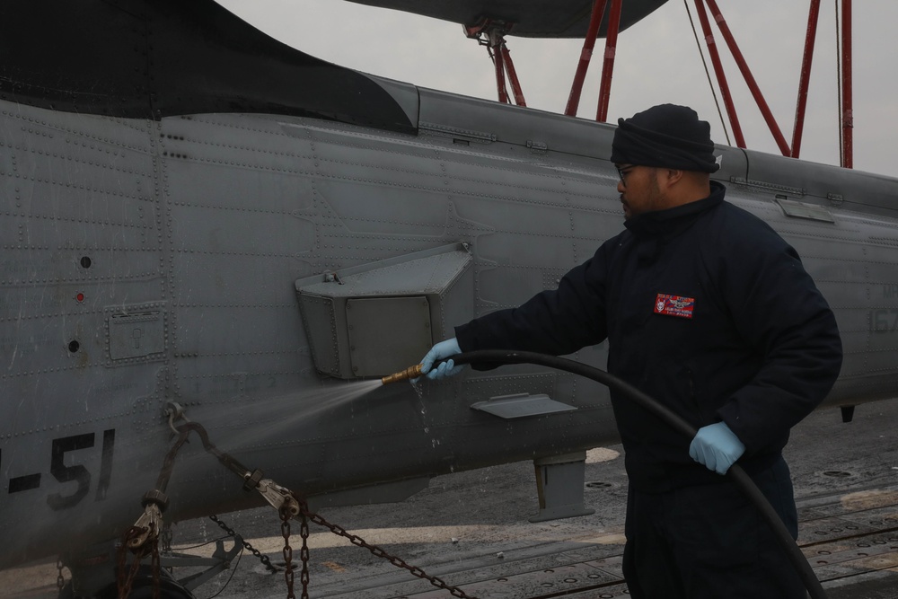 Sailors aboard the USS Rafael Peralta (DDG 115) clean a Seahawk helicopter (MH-60R) in the Sea of Japan