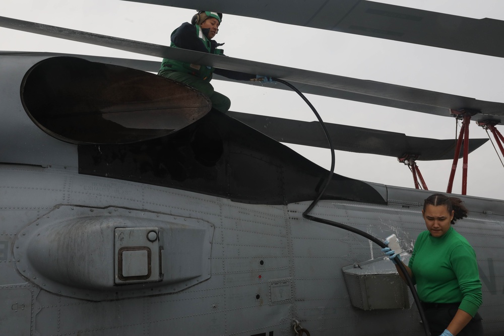 Sailors aboard the USS Rafael Peralta (DDG 115) clean a Seahawk helicopter (MH-60R) in the Sea of Japan