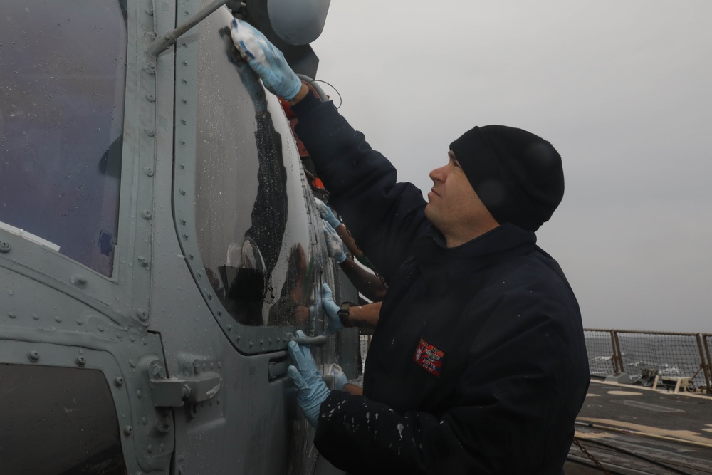 Sailors aboard the USS Rafael Peralta (DDG 115) clean a Seahawk helicopter (MH-60R) in the Sea of Japan