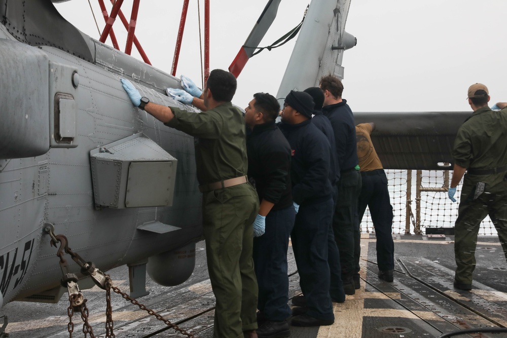 Sailors aboard the USS Rafael Peralta (DDG 115) clean a Seahawk helicopter (MH-60R) in the Sea of Japan