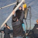 Sailors aboard the USS Rafael Peralta (DDG 115) conduct a torpedo download on the aft missile deck in the Sea of Japan