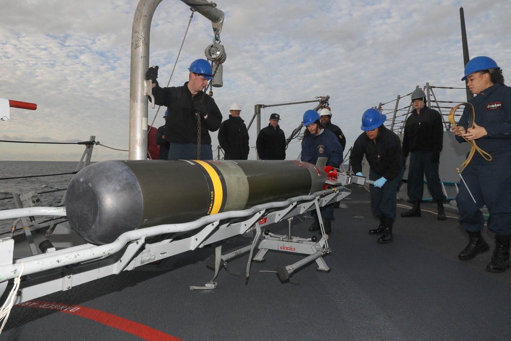 Sailors aboard the USS Rafael Peralta (DDG 115) conduct a torpedo download on the aft missile deck in the Sea of Japan