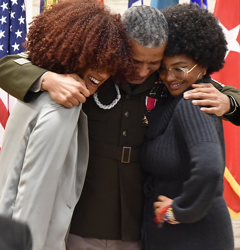 Sgt. Maj. Felix Lassus gives his daughters a big hug after a retirement ceremony