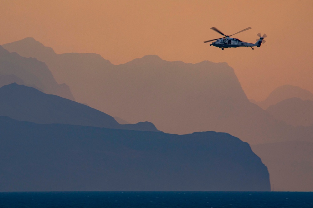 A MH-60 Helicopter flies over Mountains in the Strait of Hormuz