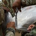 Many hands make light work: Deployed Airmen train to assist mortuary specialists with a full body wrap