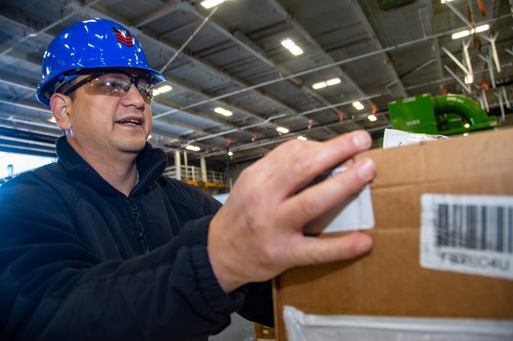 USS Ronald Reagan (CVN 76) Sailors sort supply packages for ship departments