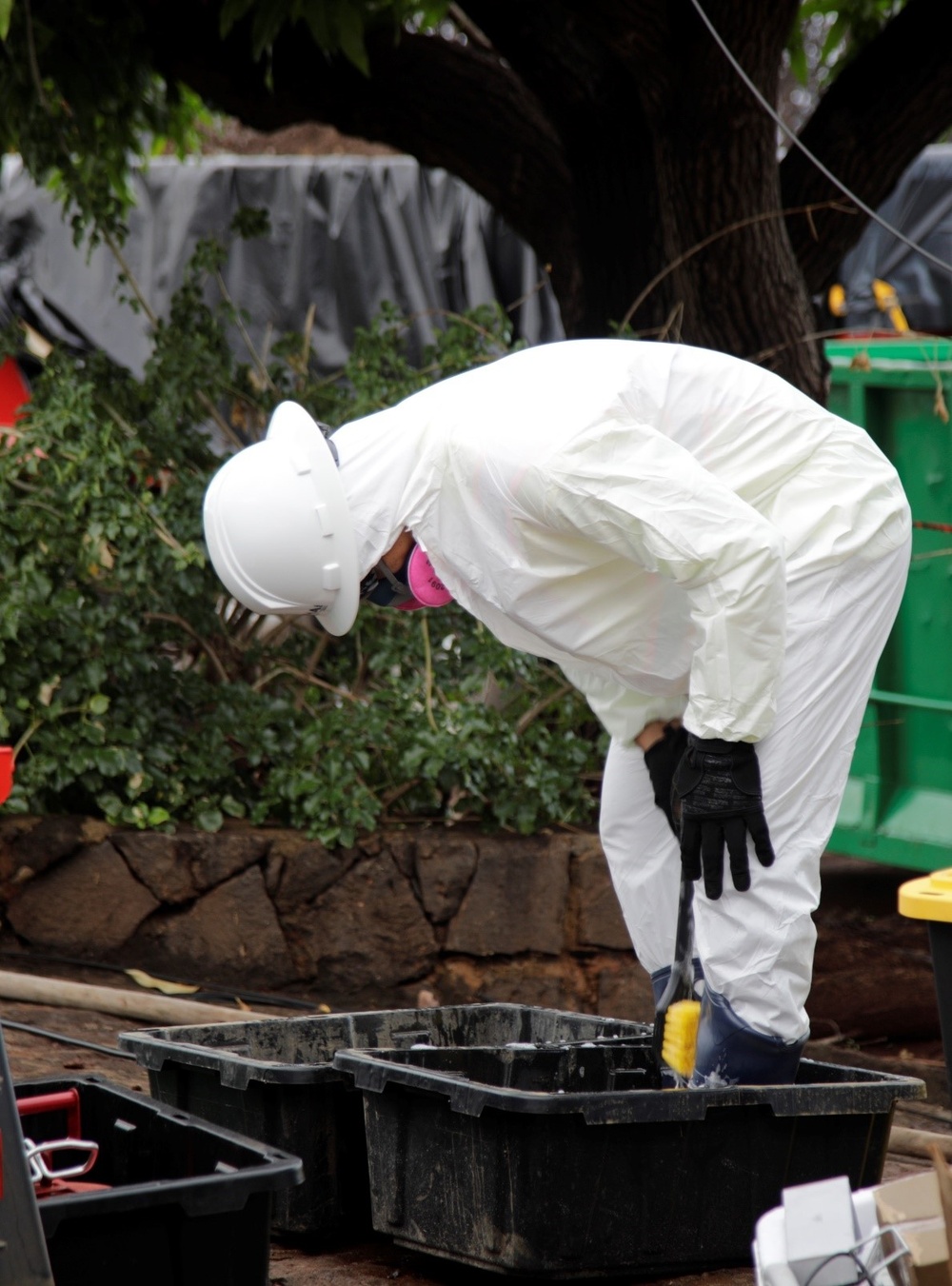 A worker cleans their boots in the contamination reduction zone