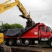 An excavator places debris in a dump truck for hauling to the Temporary Debris Storage site