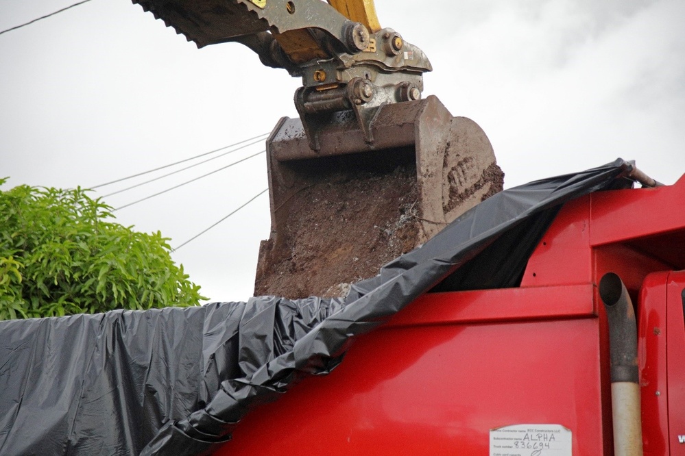 A bucket loads debris into a dump truck for transport to the Temporary Debris Storage site