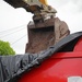 A bucket loads debris into a dump truck for transport to the Temporary Debris Storage site