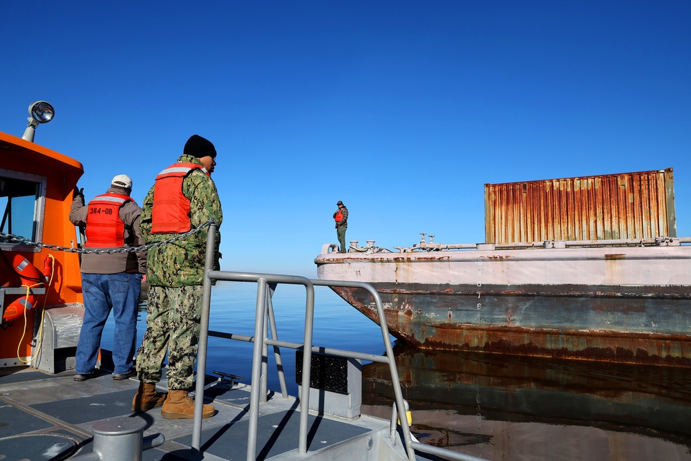 Decommissioned World War II-era fuel barge undergoing a maneuverability test to determine its towing capabilities.