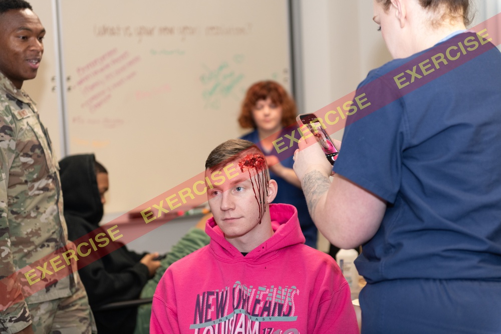 A simulated accident victim poses for photos of his moulage wounds.