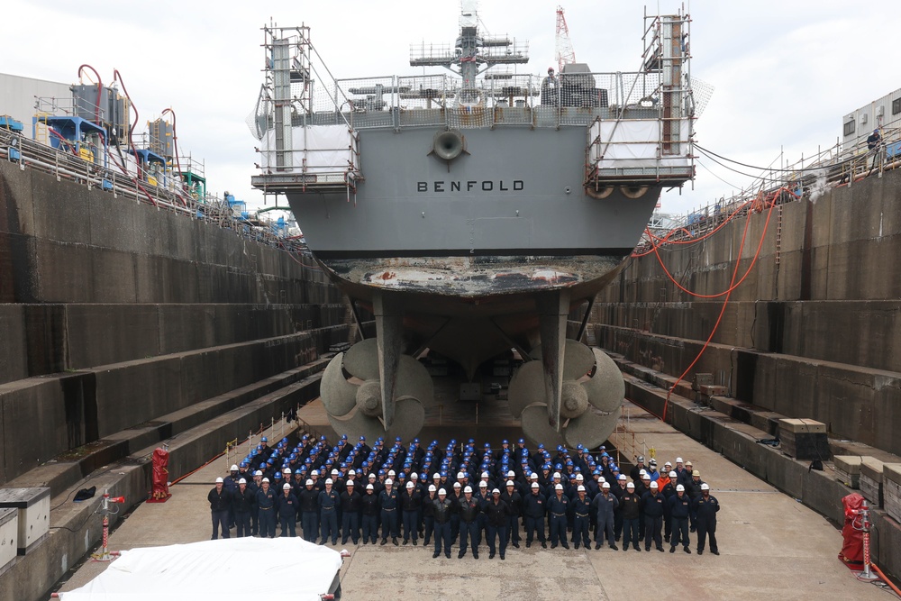 The crew of the USS Benfold (DDG 65) pose for a group photo in a dry dock onboard Commander, Fleet Activities Yokosuka